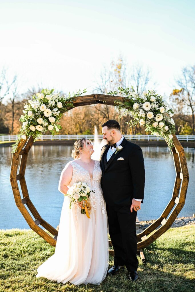 Bride & Groom post for wedding day photos by our pond & fountain outdoor, garden wedding ceremony.