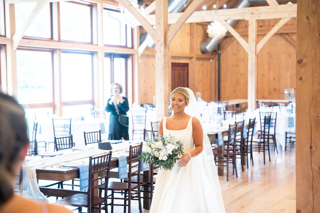 Spring bride wearing a designer wedding dress, holding a luxury bouquet of flowers as she enjoys a first look at the elegant wedding reception space at our historic wedding venue near Philadelphia