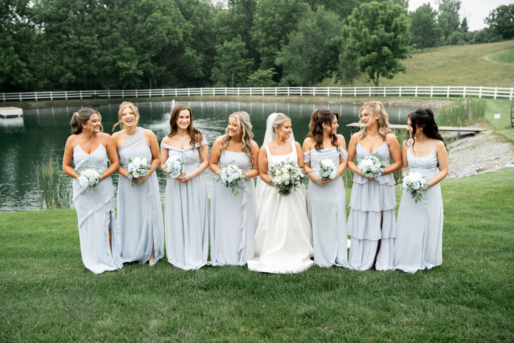 Beautiful spring bride and bridesmaids wearing blue bridesmaid dresses and holding elegant spring wedding flowers at our outdoor wedding ceremony near Philly